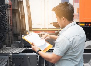 Truck driver holding clipboard inspecting safety vehicle maintenance checklist a truck trailer, Road freight industry logistics